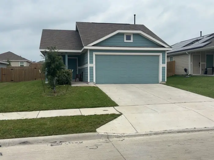 Front lawn and driveway finished at a home with teal siding