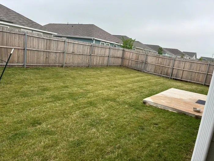Wide fenced back yard mown flat and clear of clippings