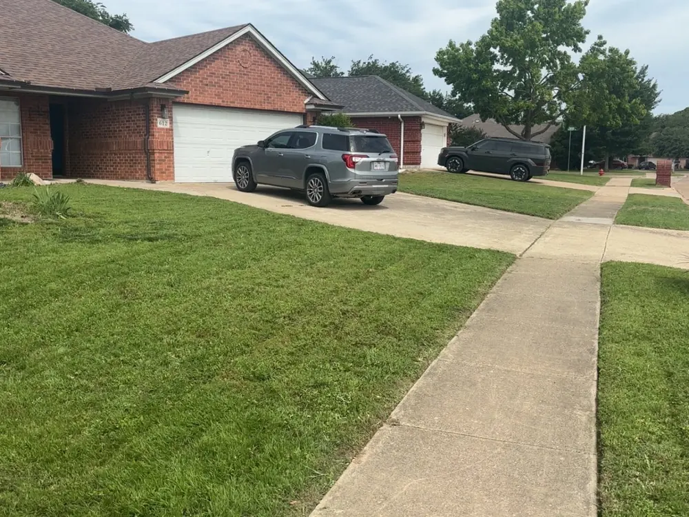 Front lawn mowed with clean stripes and an edged driveway in Saginaw, TX